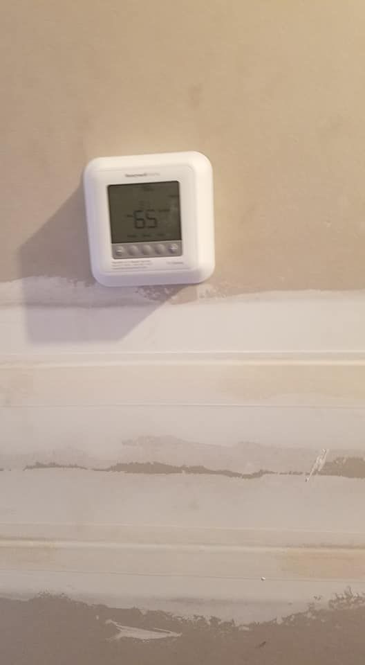 A white thermostat is mounted on a wall