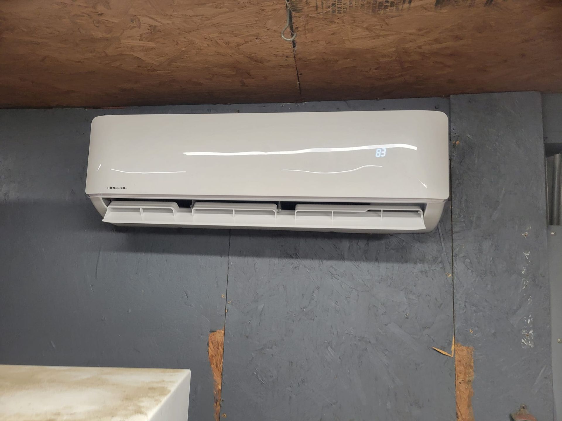 A white air conditioner is hanging on a wall in a room