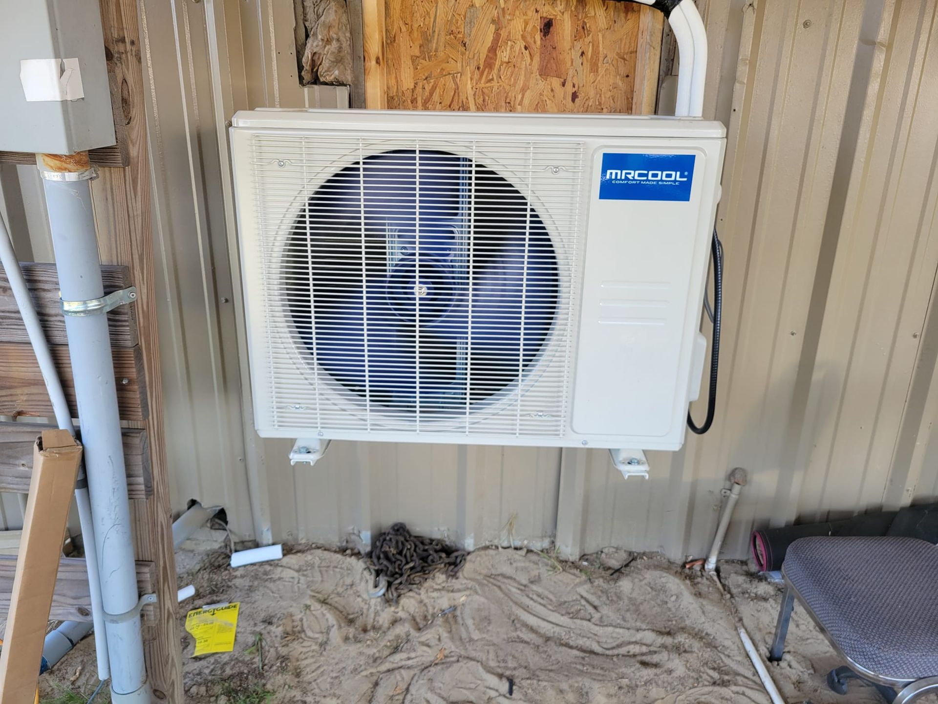 A white air conditioner is mounted on the side of a building.