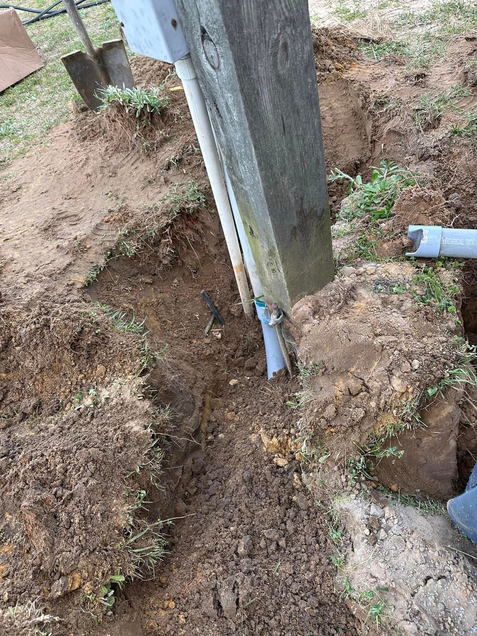 A shovel is digging a hole in the ground next to a pole.