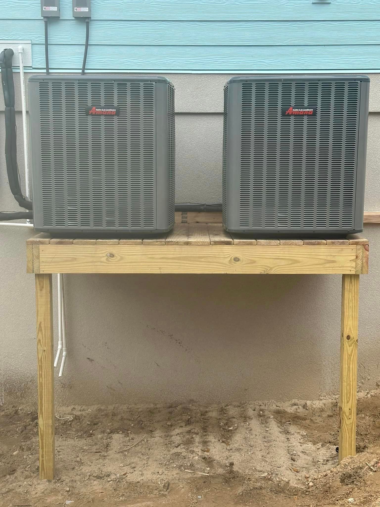 Two air conditioners are sitting on top of a wooden table