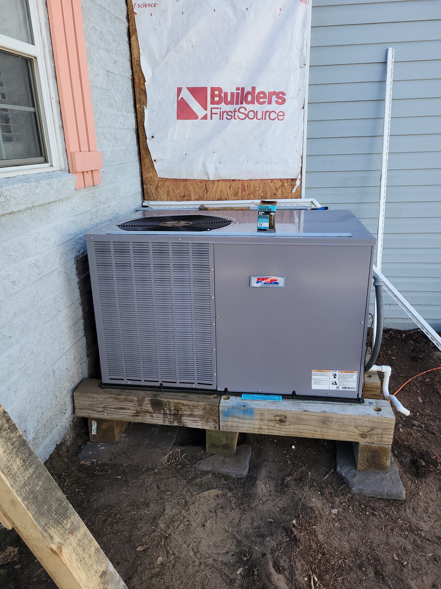 An air conditioner sits on top of a wooden platform