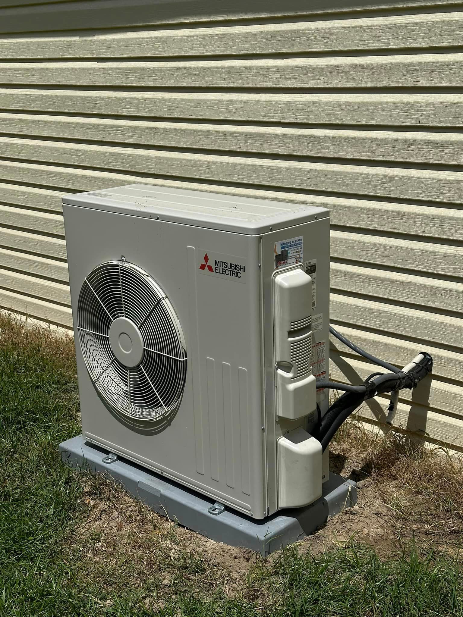 A white air conditioner is sitting on the side of a house