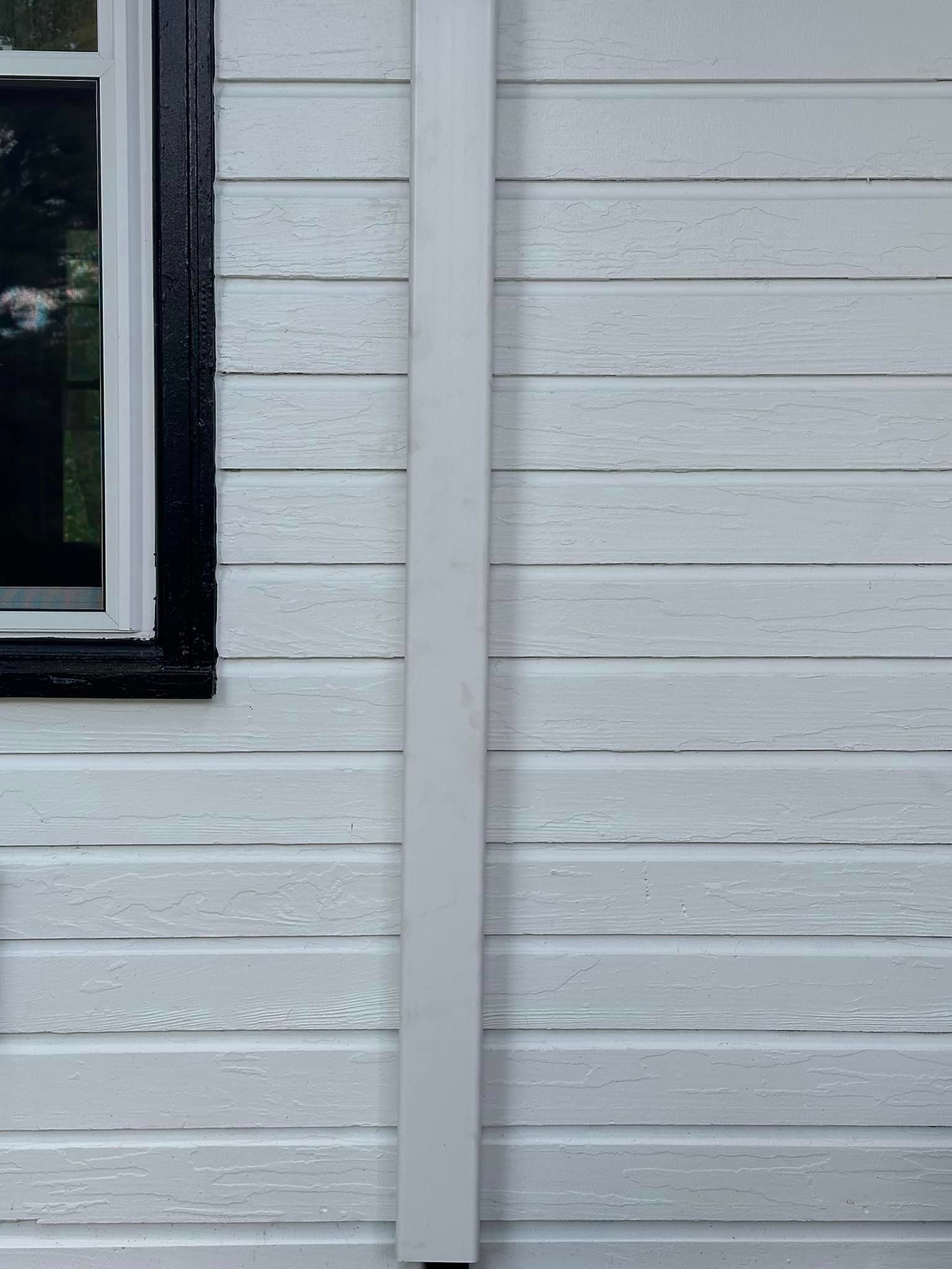 A white house with a black window and a white gutter on the side