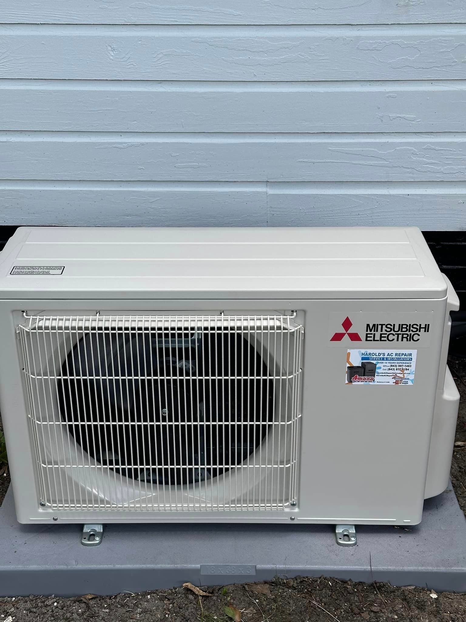 A mitsubishi air conditioner is sitting outside of a building