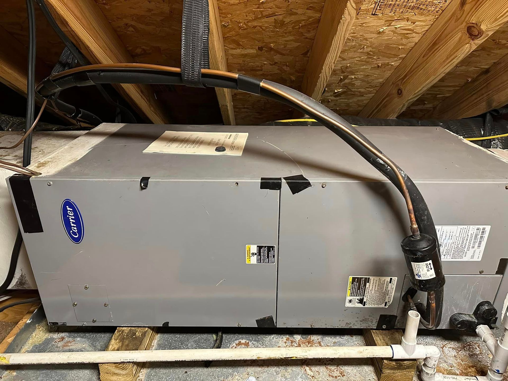 A carrier air conditioner is sitting in the attic of a house.