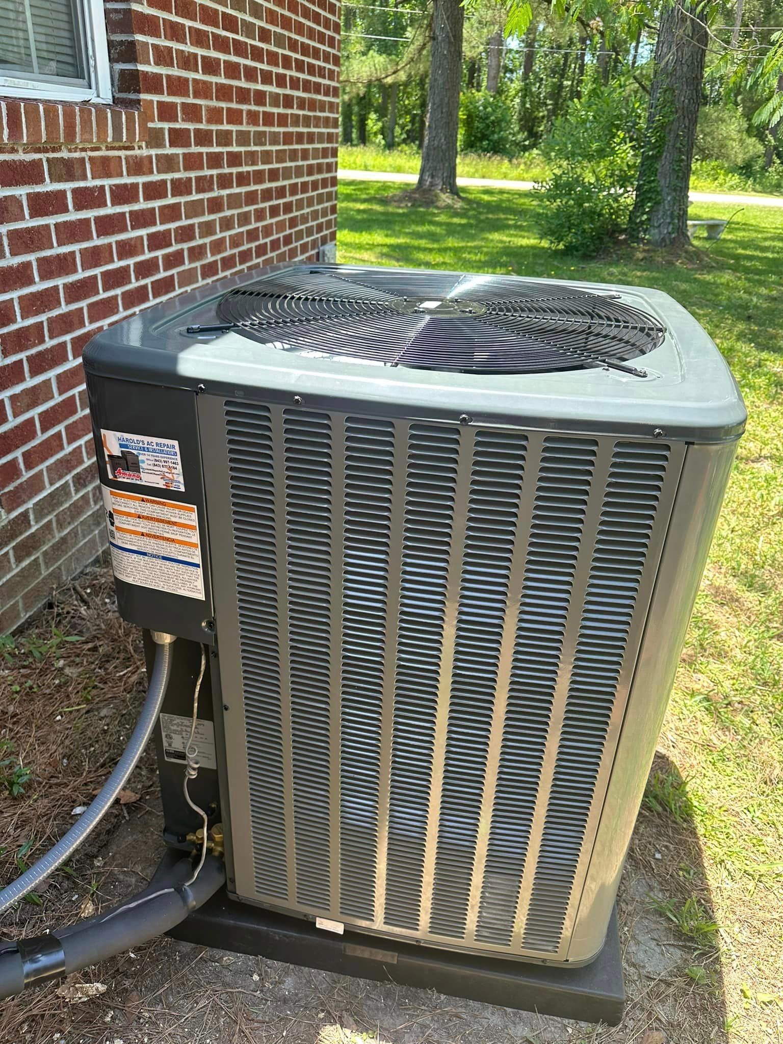 A large air conditioner is sitting on the side of a brick building.