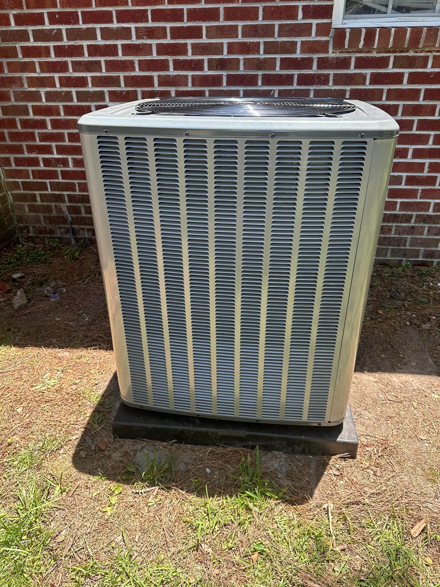 A large air conditioner is sitting in front of a brick building