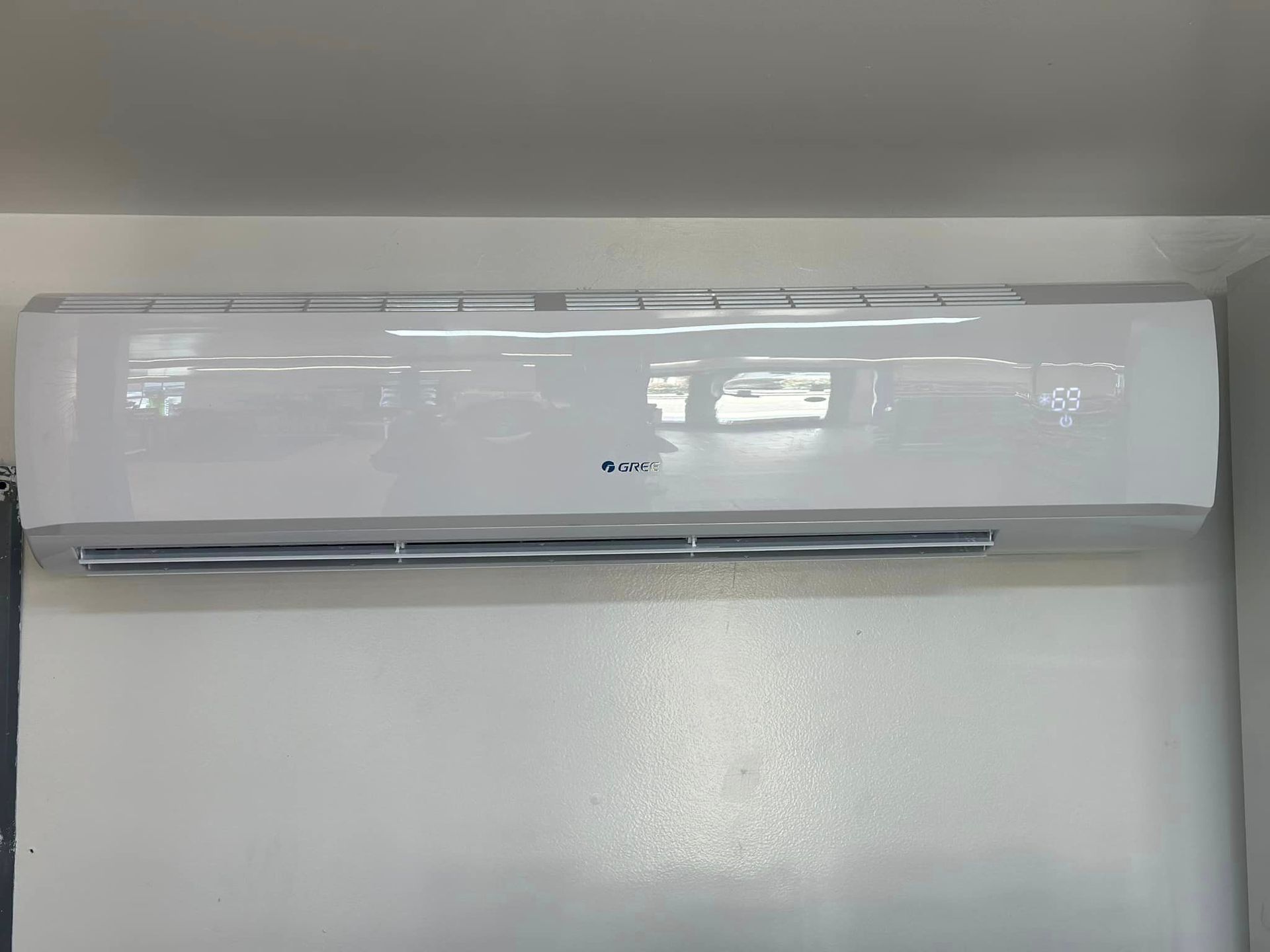 A white air conditioner is hanging on a white wall