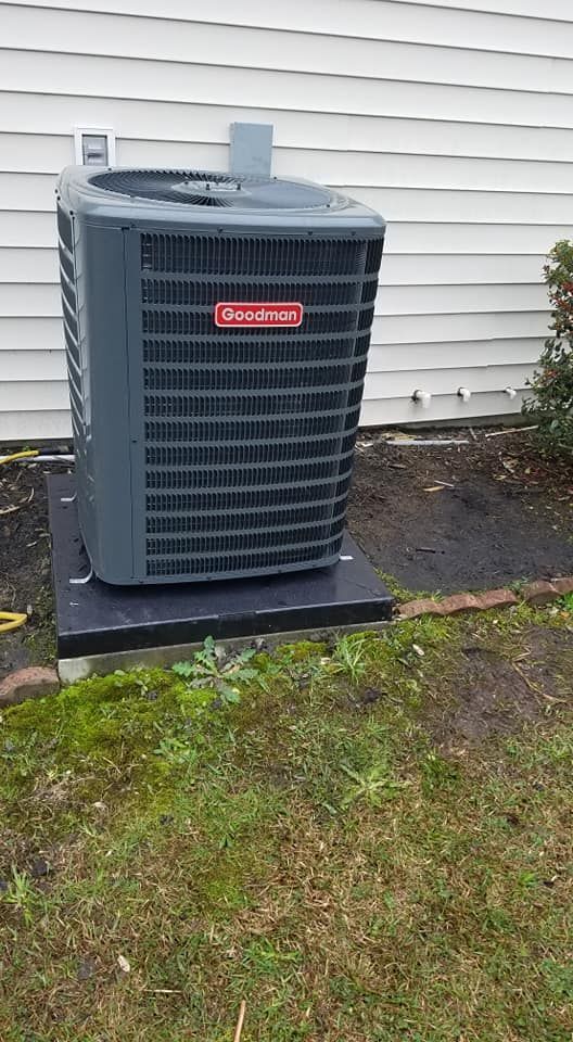 A large air conditioner is sitting on top of a concrete platform in front of a house