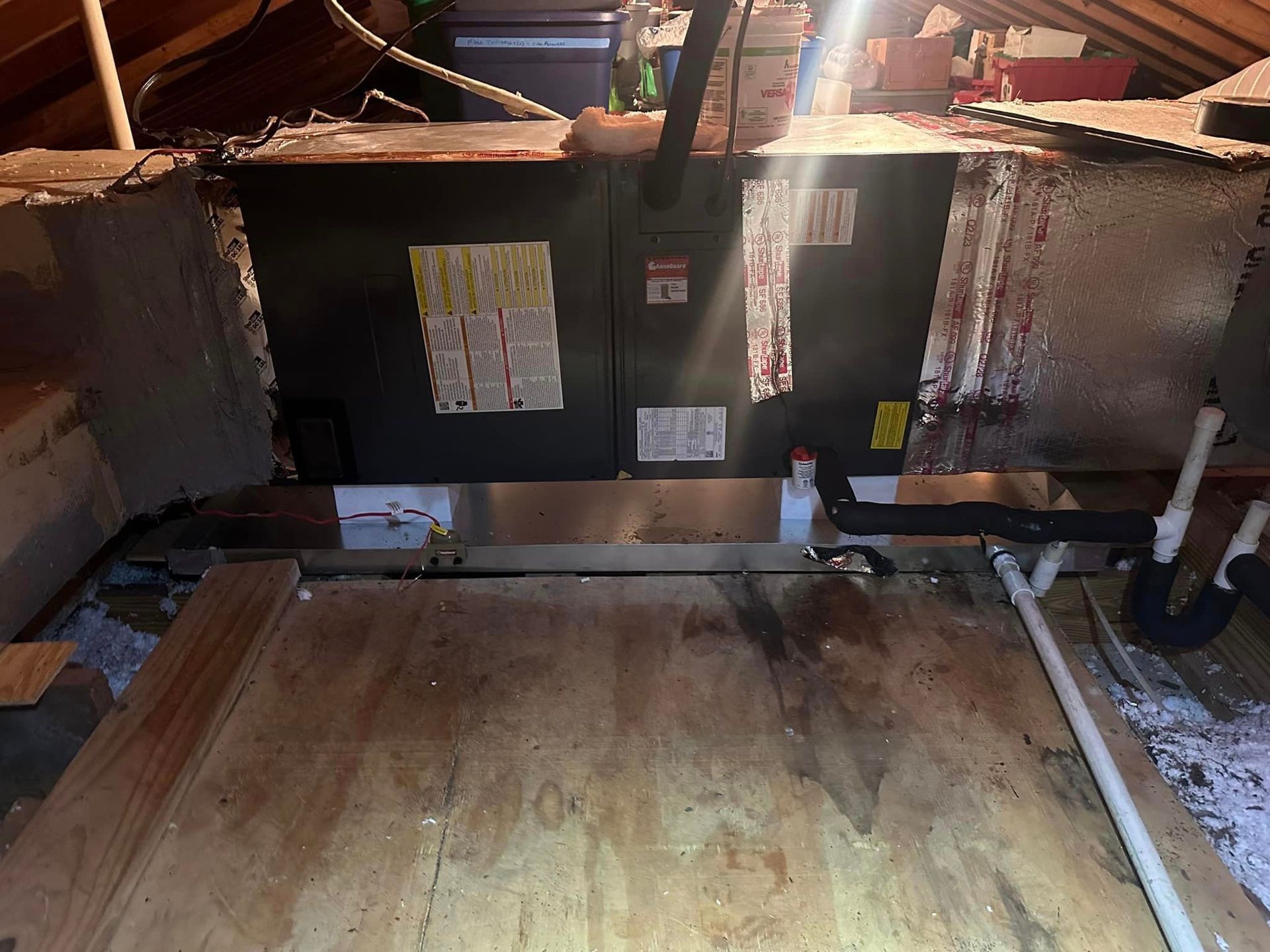 A black box is sitting on top of a wooden floor in an attic