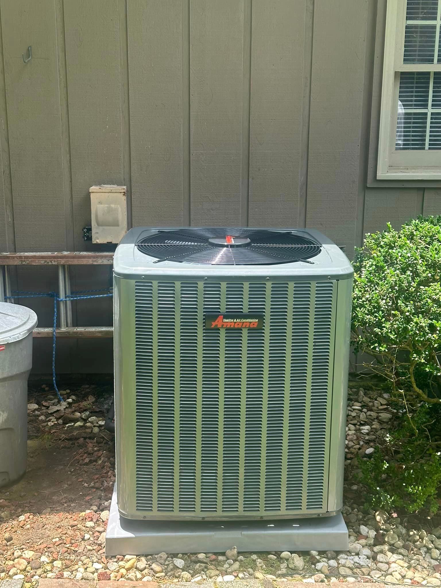 An air conditioner is sitting outside of a house next to a window