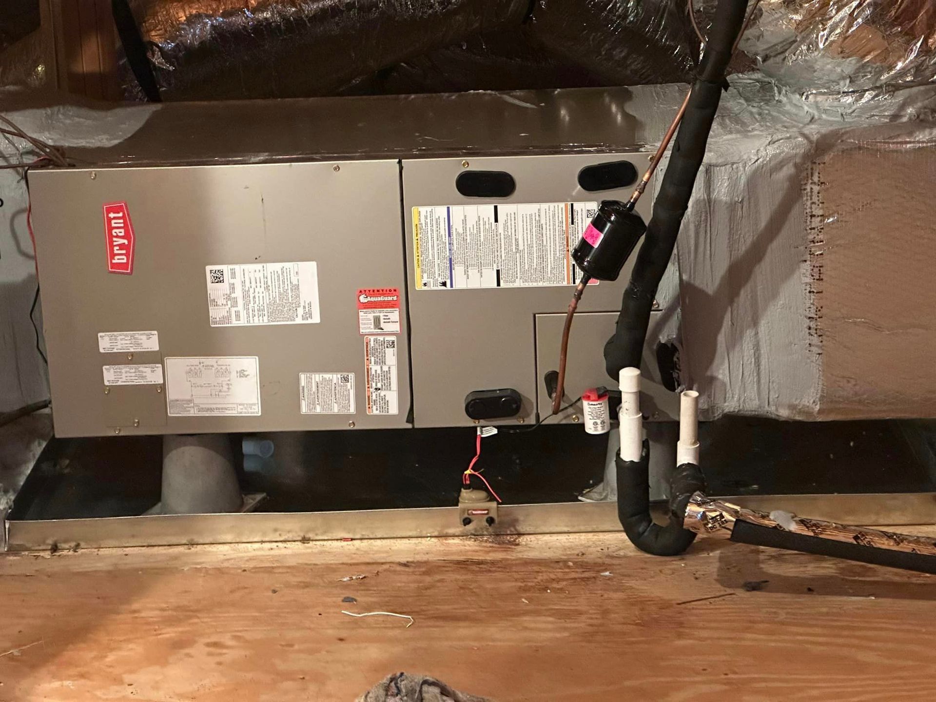 An air conditioner is sitting on top of a wooden floor in a room