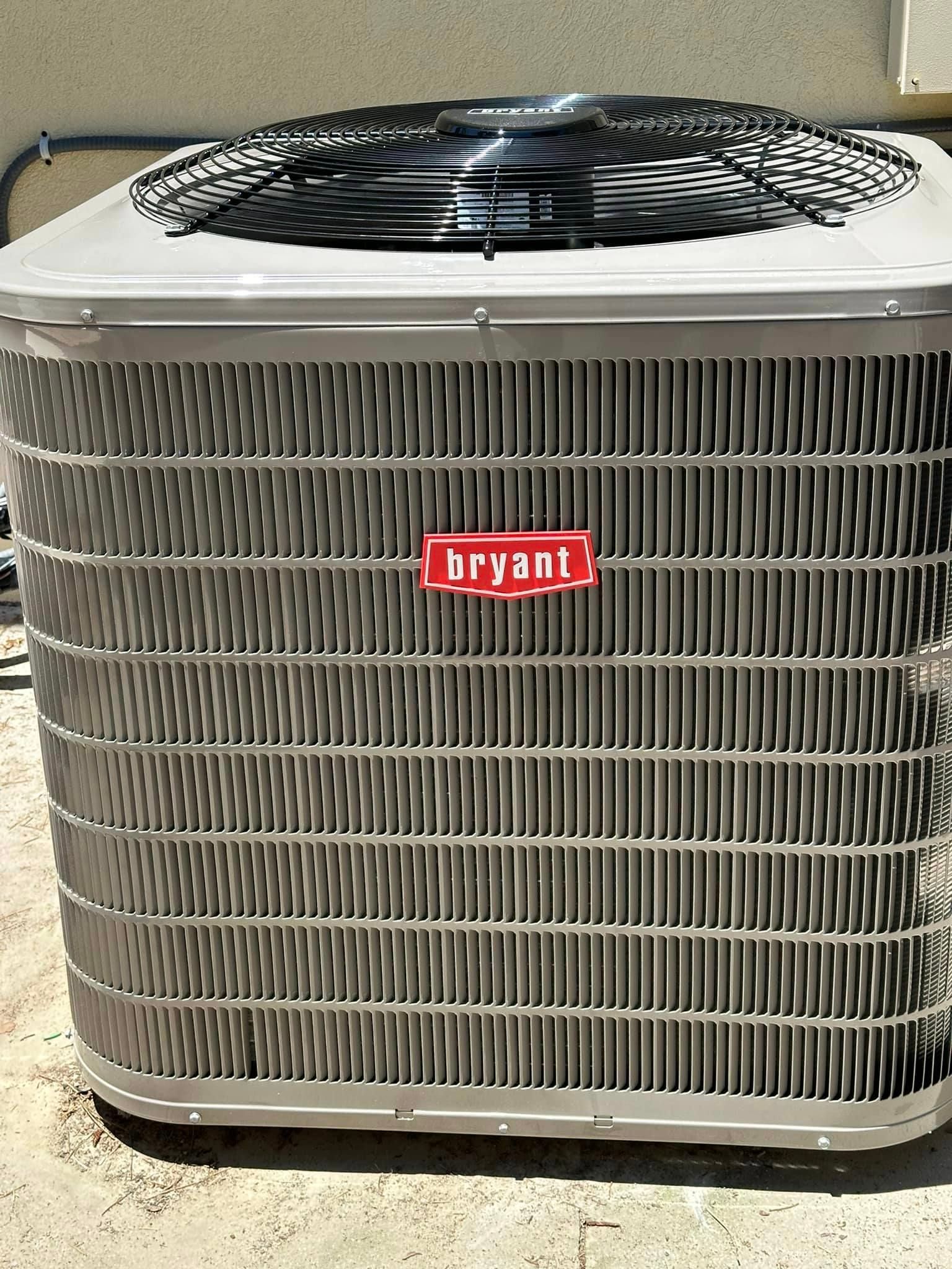 A bryant air conditioner is sitting on the ground outside of a building