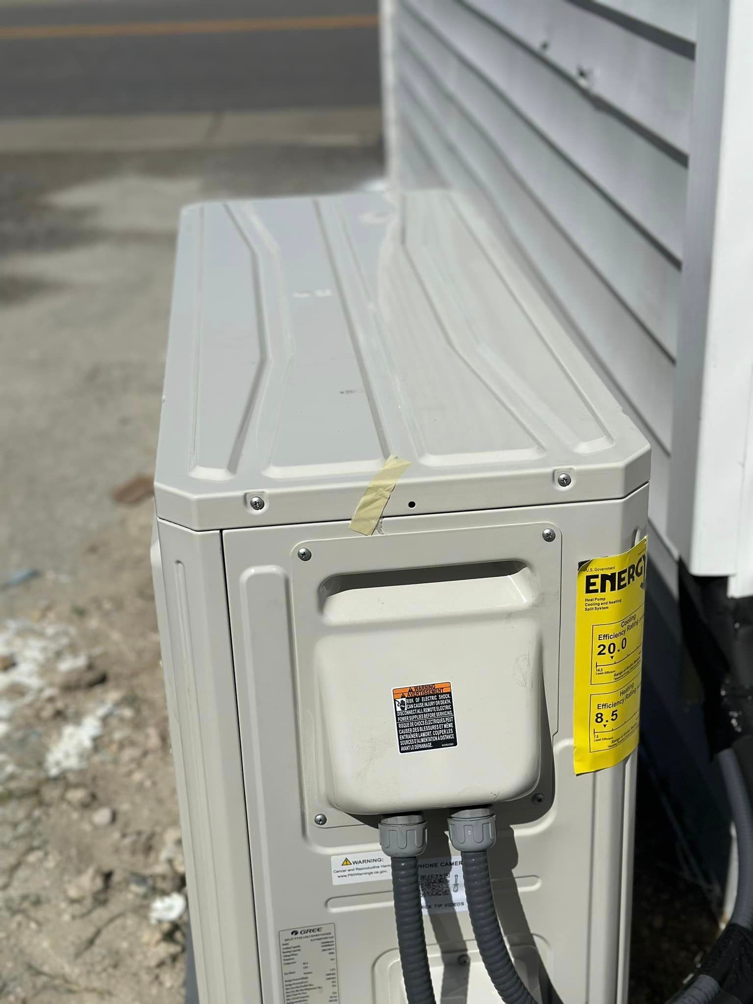 A white air conditioner is sitting on the side of a house