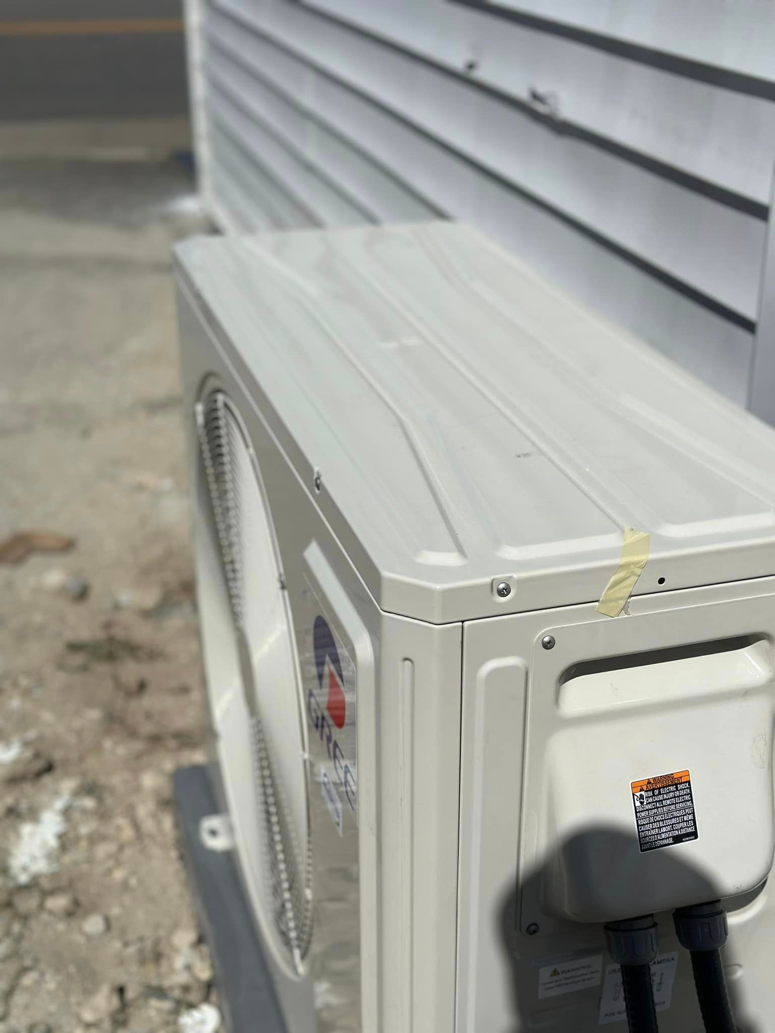 A white air conditioner is sitting on the side of a building