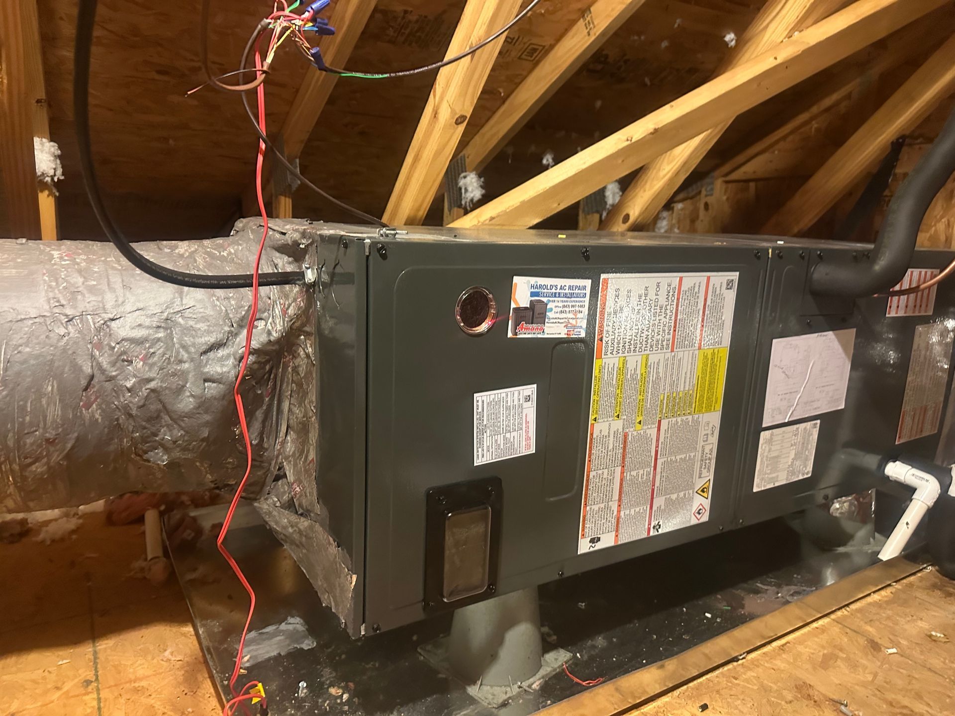 An air conditioner is sitting in the attic of a house.