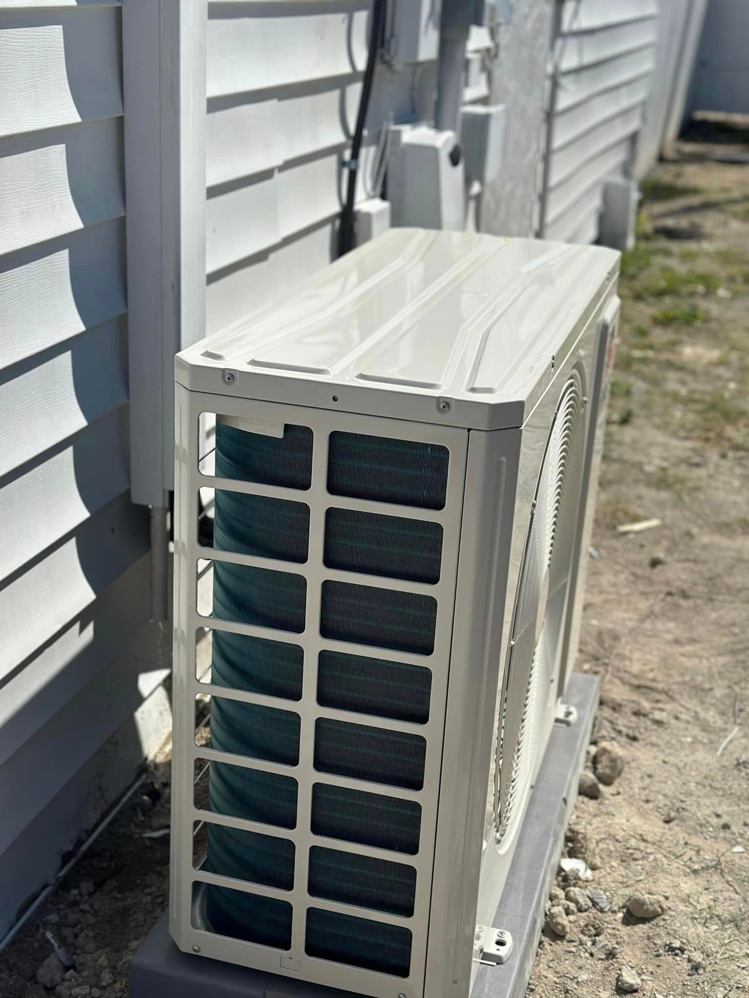A white air conditioner is sitting on the side of a house
