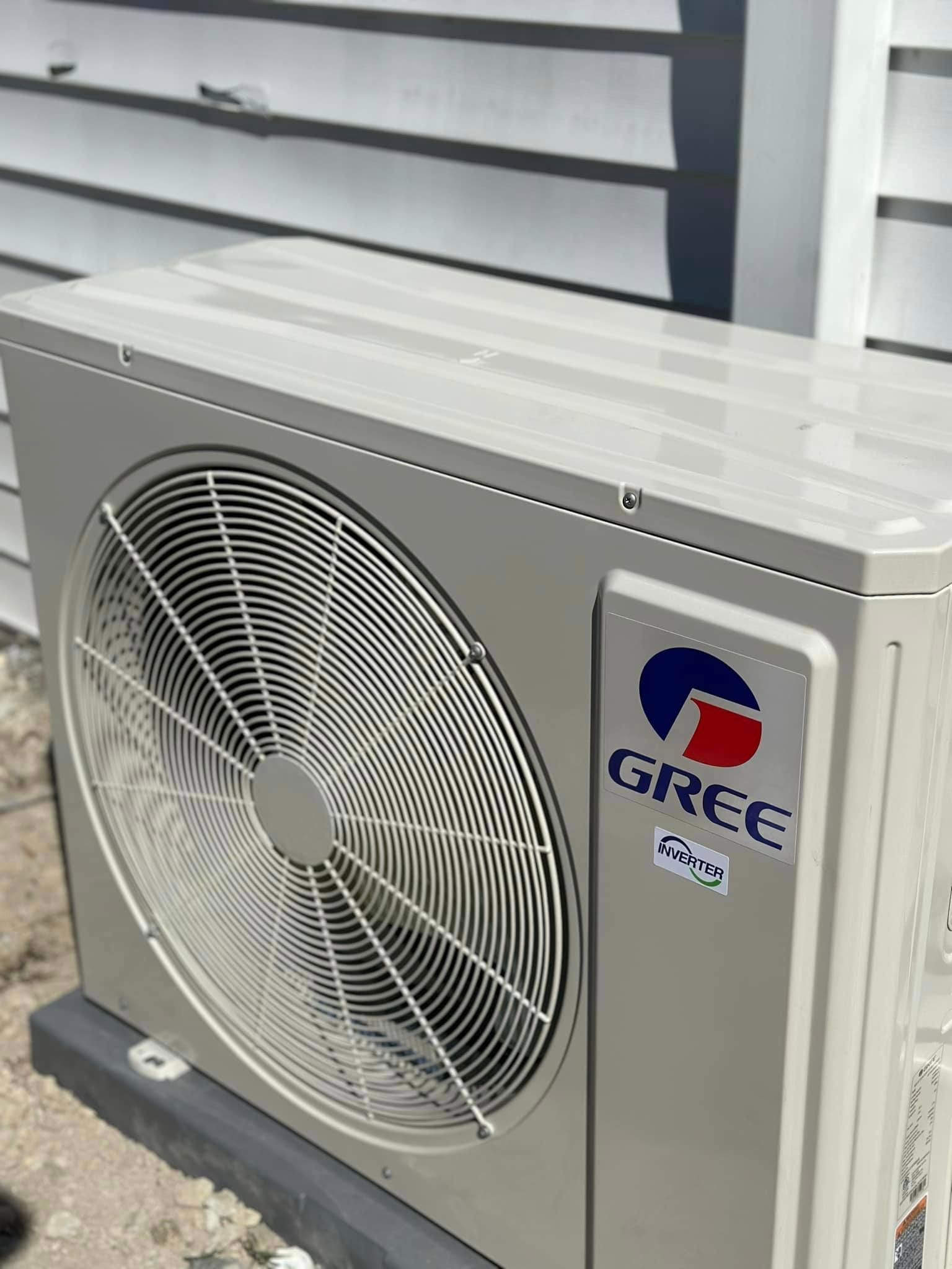 A gree air conditioner is sitting outside of a building