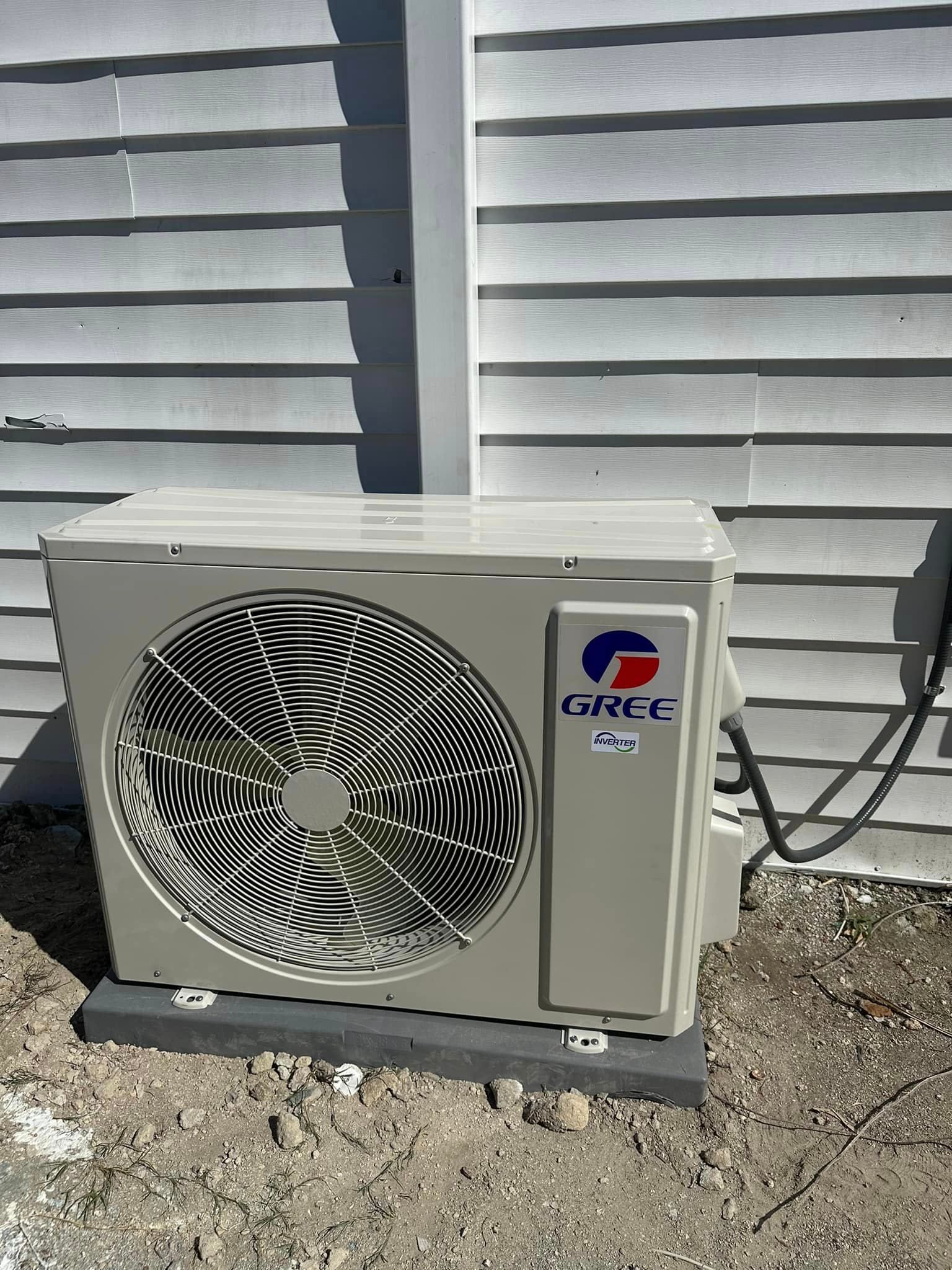 A gree air conditioner is sitting outside of a house