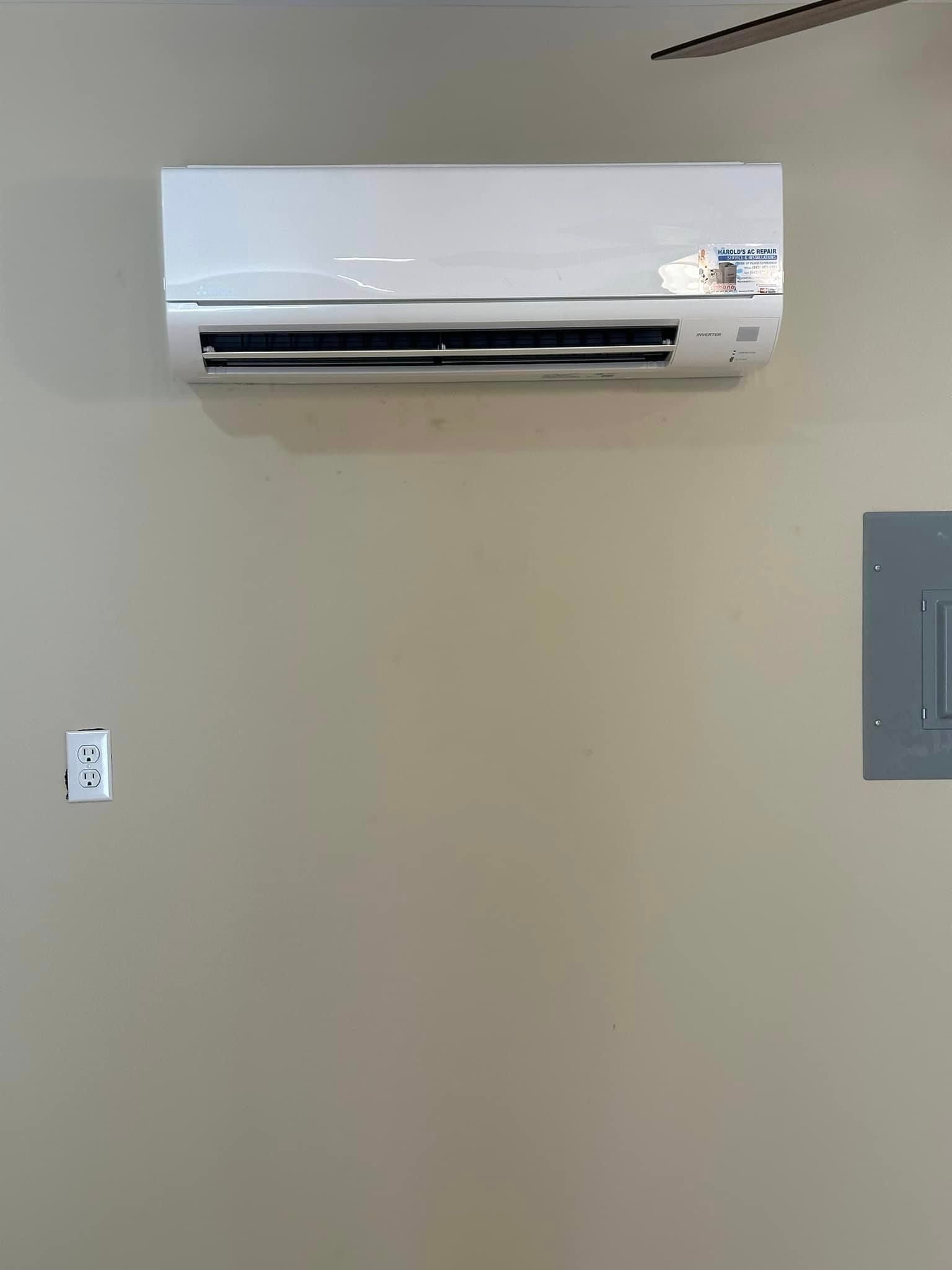 A white air conditioner is hanging on a wall in a room