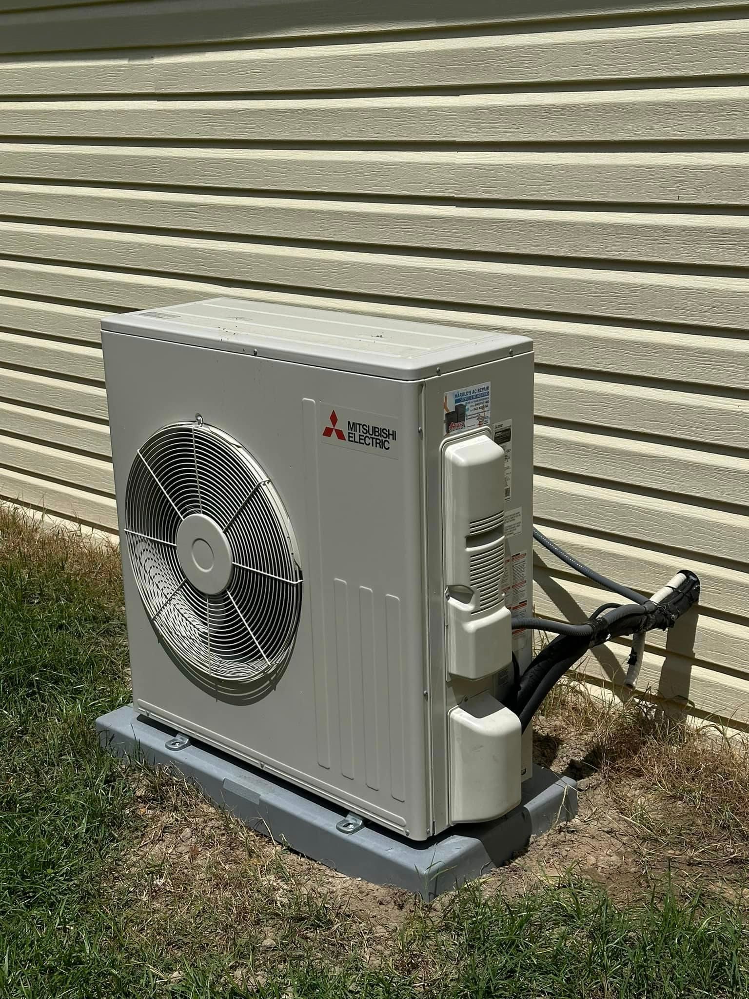 A white air conditioner is sitting on the side of a house