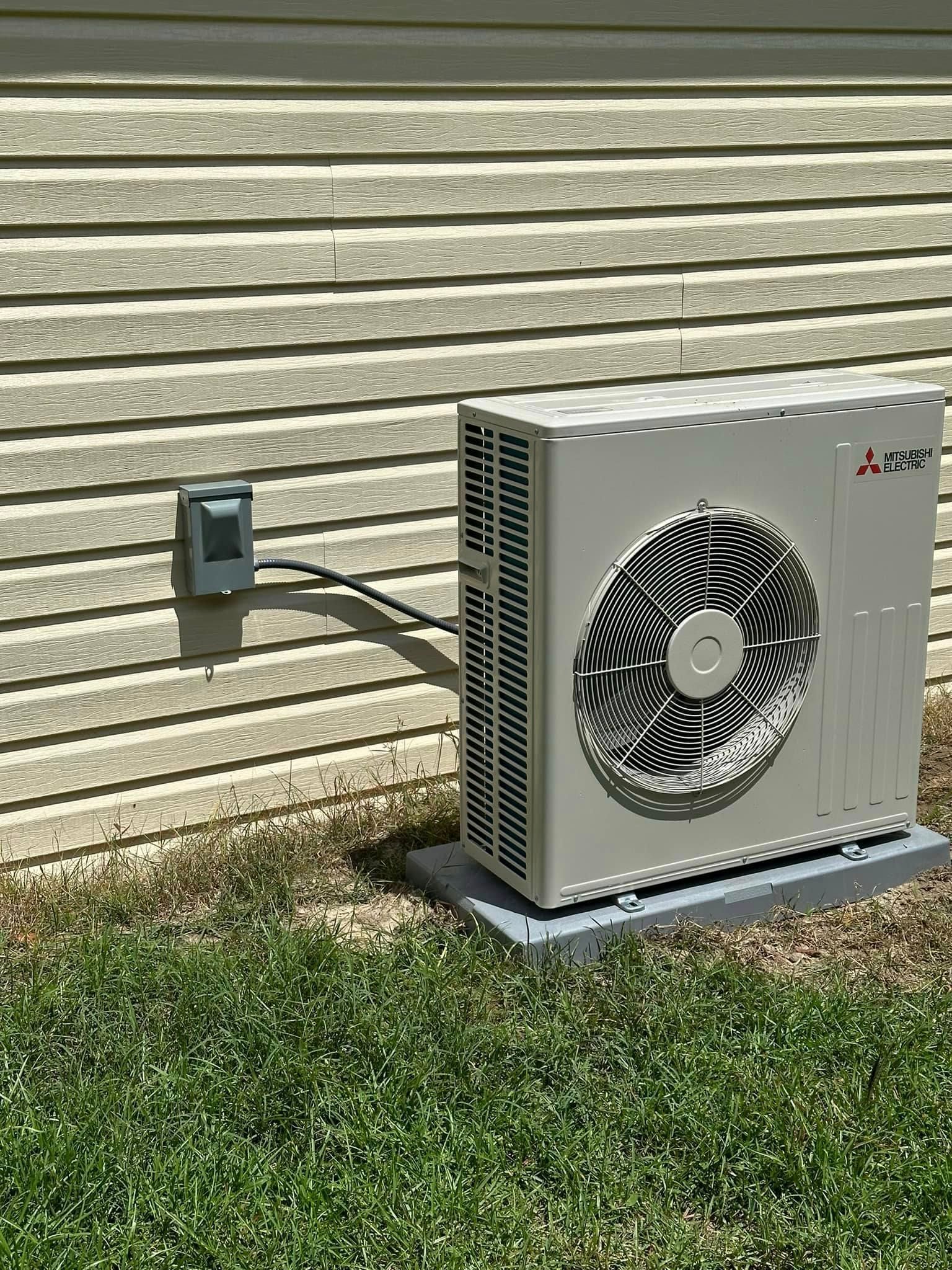 A white air conditioner is mounted on the side of a house