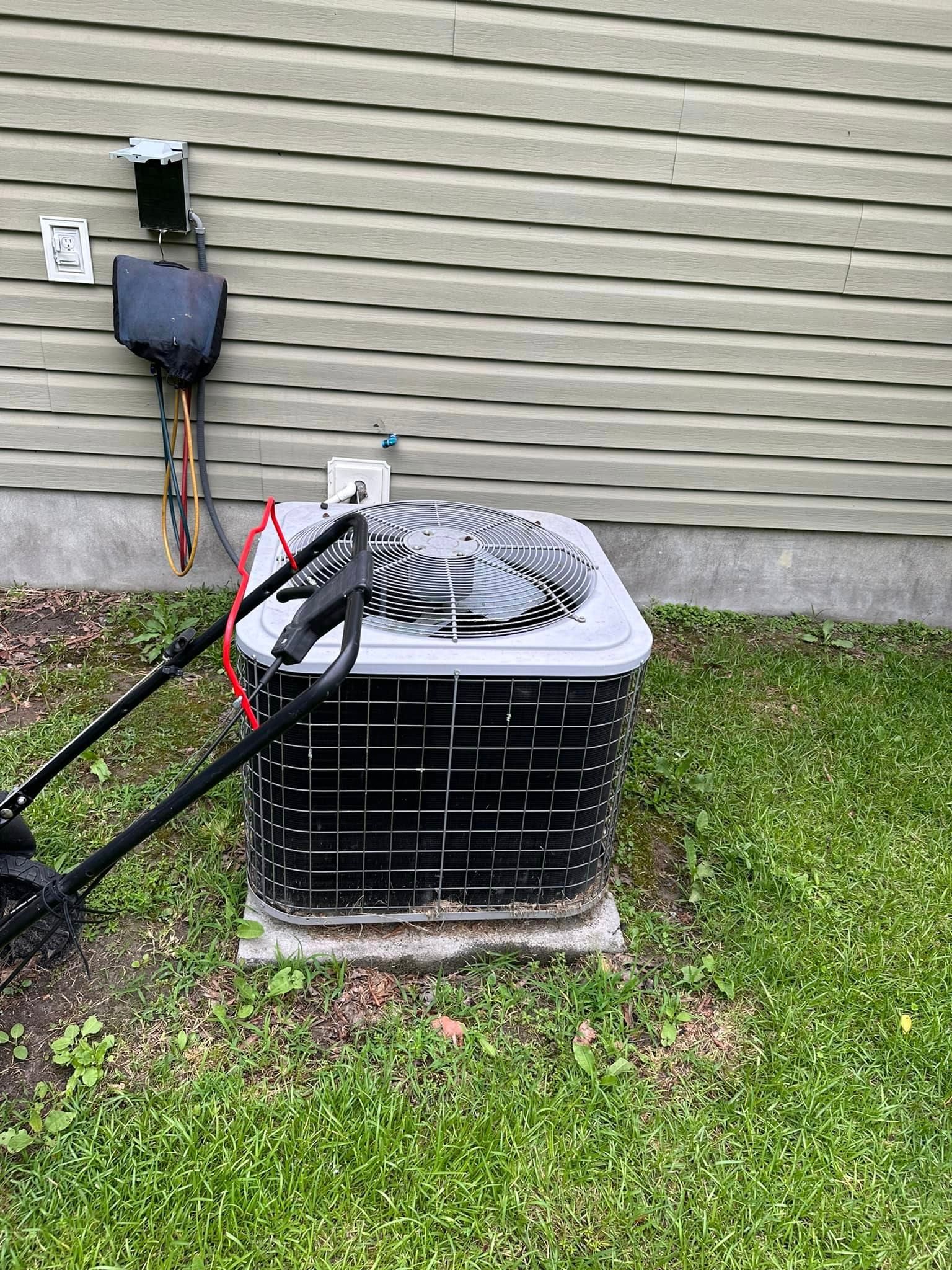 An air conditioner is sitting in the grass in front of a house