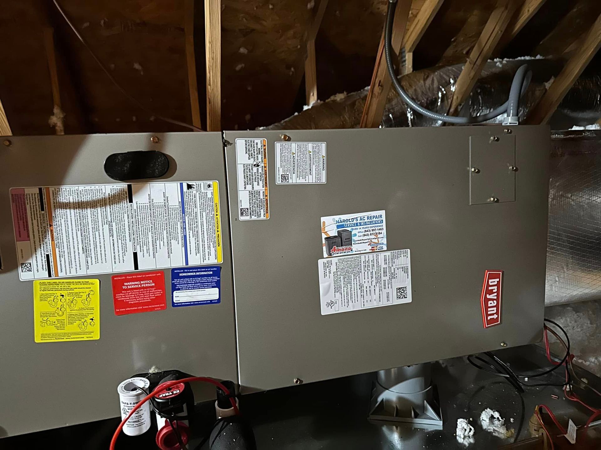 A refrigerator with a lot of stickers on it is sitting in the attic
