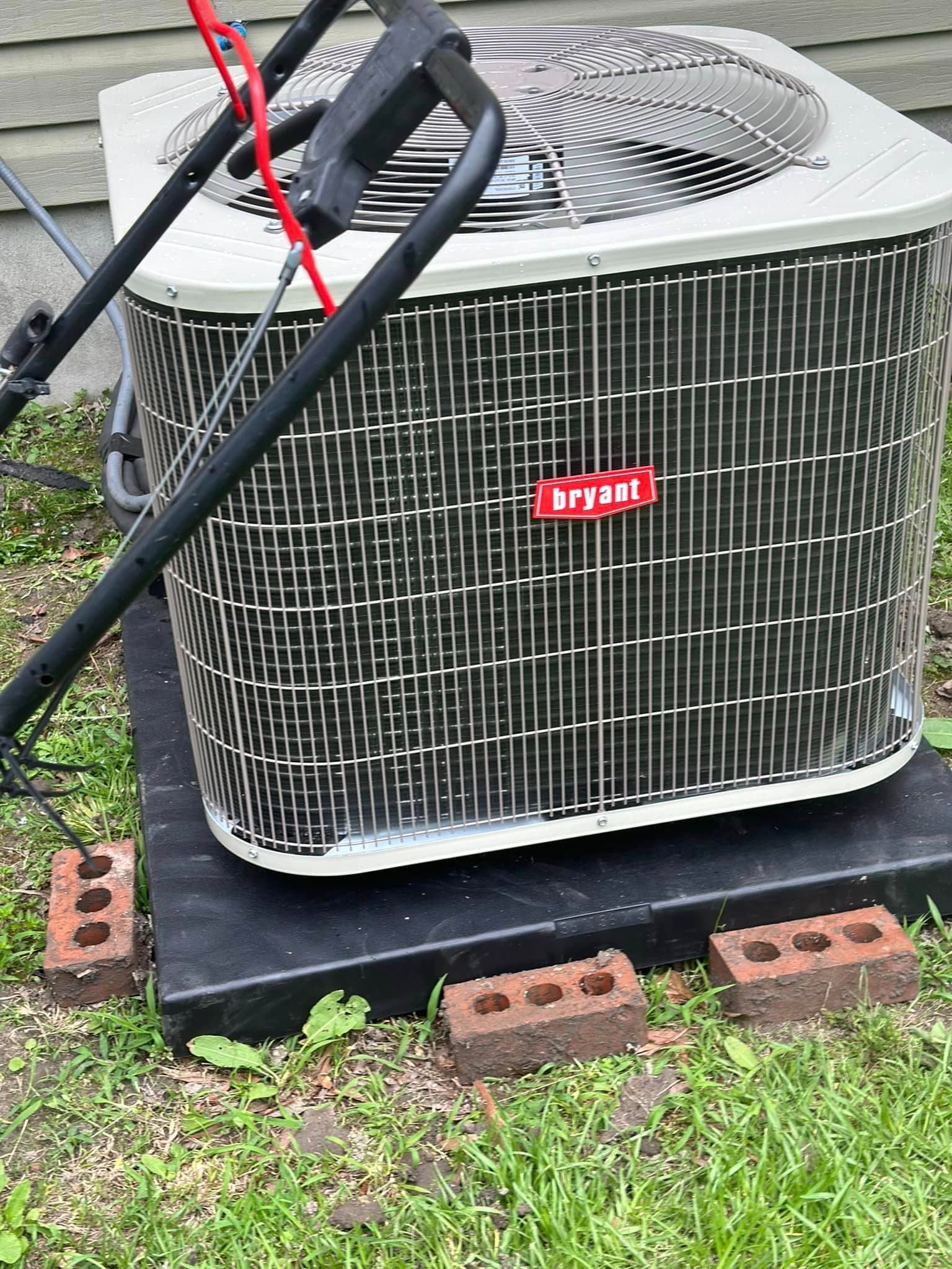 A lawn mower is sitting next to an air conditioner