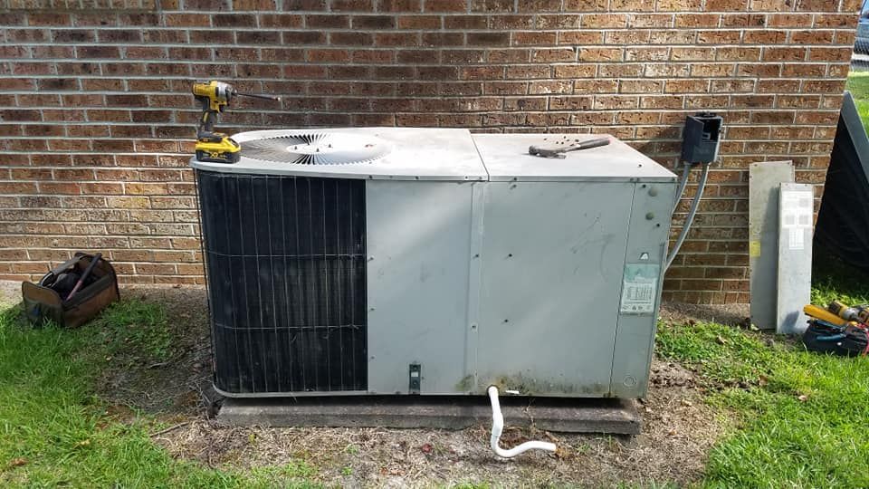 A large air conditioner is sitting in front of a brick wall