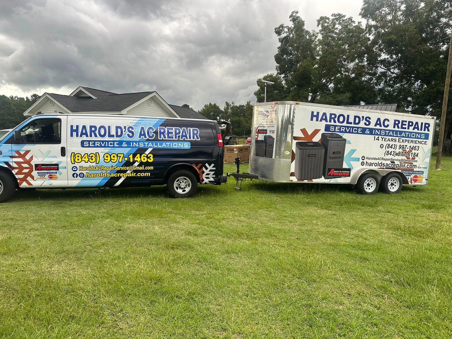 A van and trailer are parked in a grassy field.