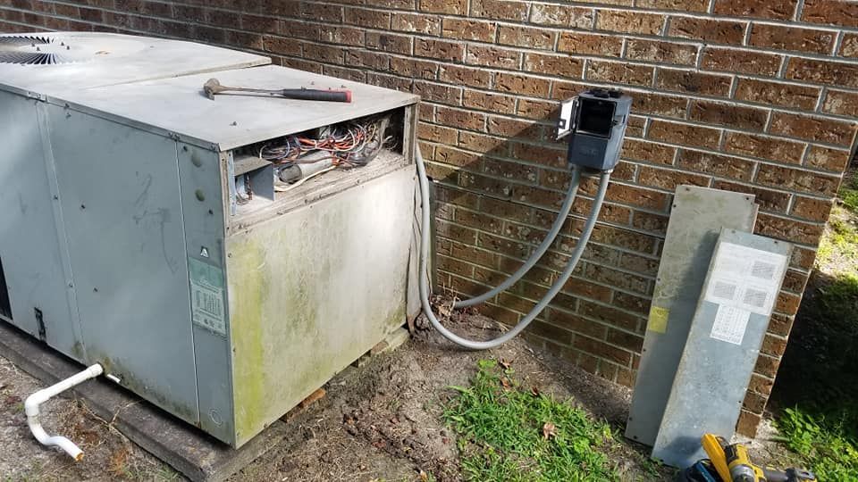 An air conditioner is sitting on the side of a brick building