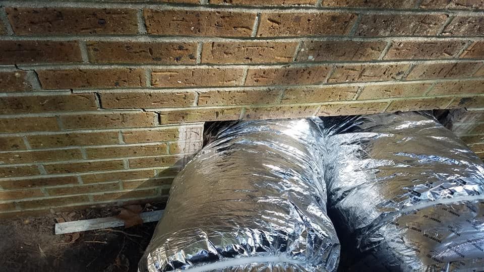 A duct is being installed in a hole in a brick wall