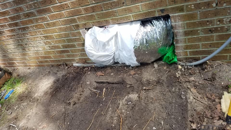 A brick wall with a hole in it and a bag covering it