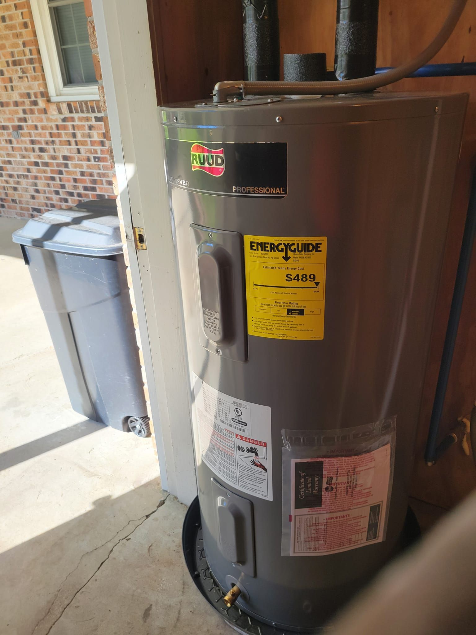 A water heater is sitting in a garage next to a brick wall