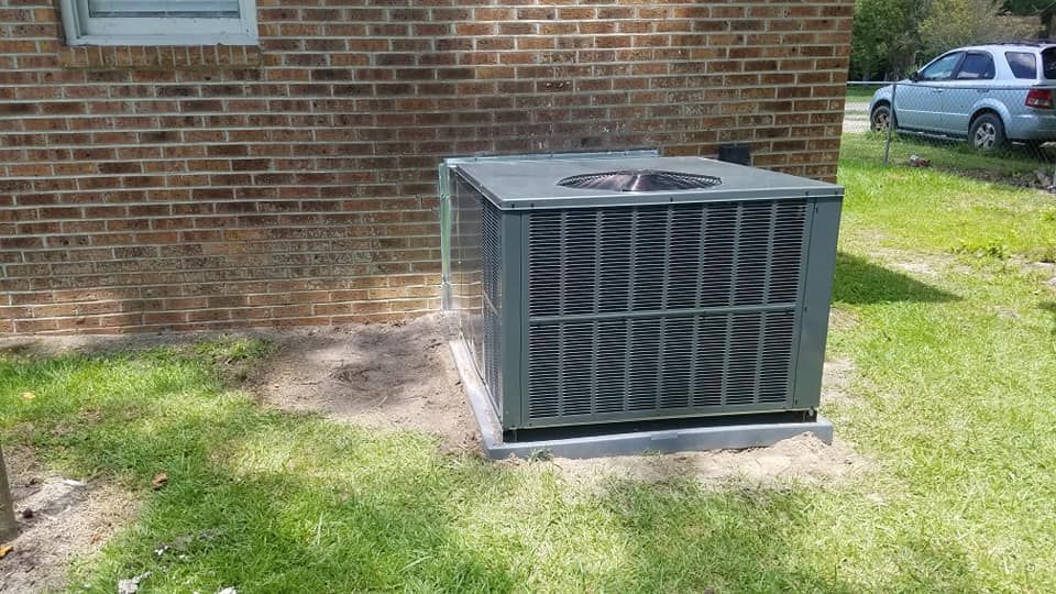 A large air conditioner is sitting on the side of a brick building
