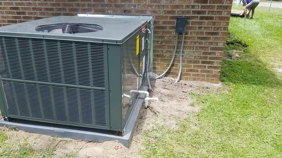 A large air conditioner is sitting on the side of a brick building