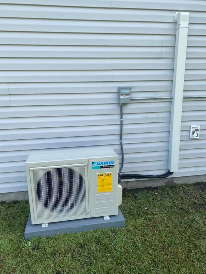 A white air conditioner is mounted on the side of a house
