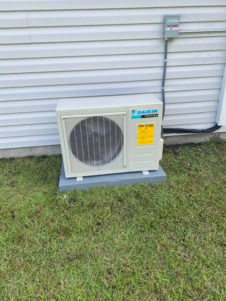 A daikin air conditioner is sitting on the side of a house