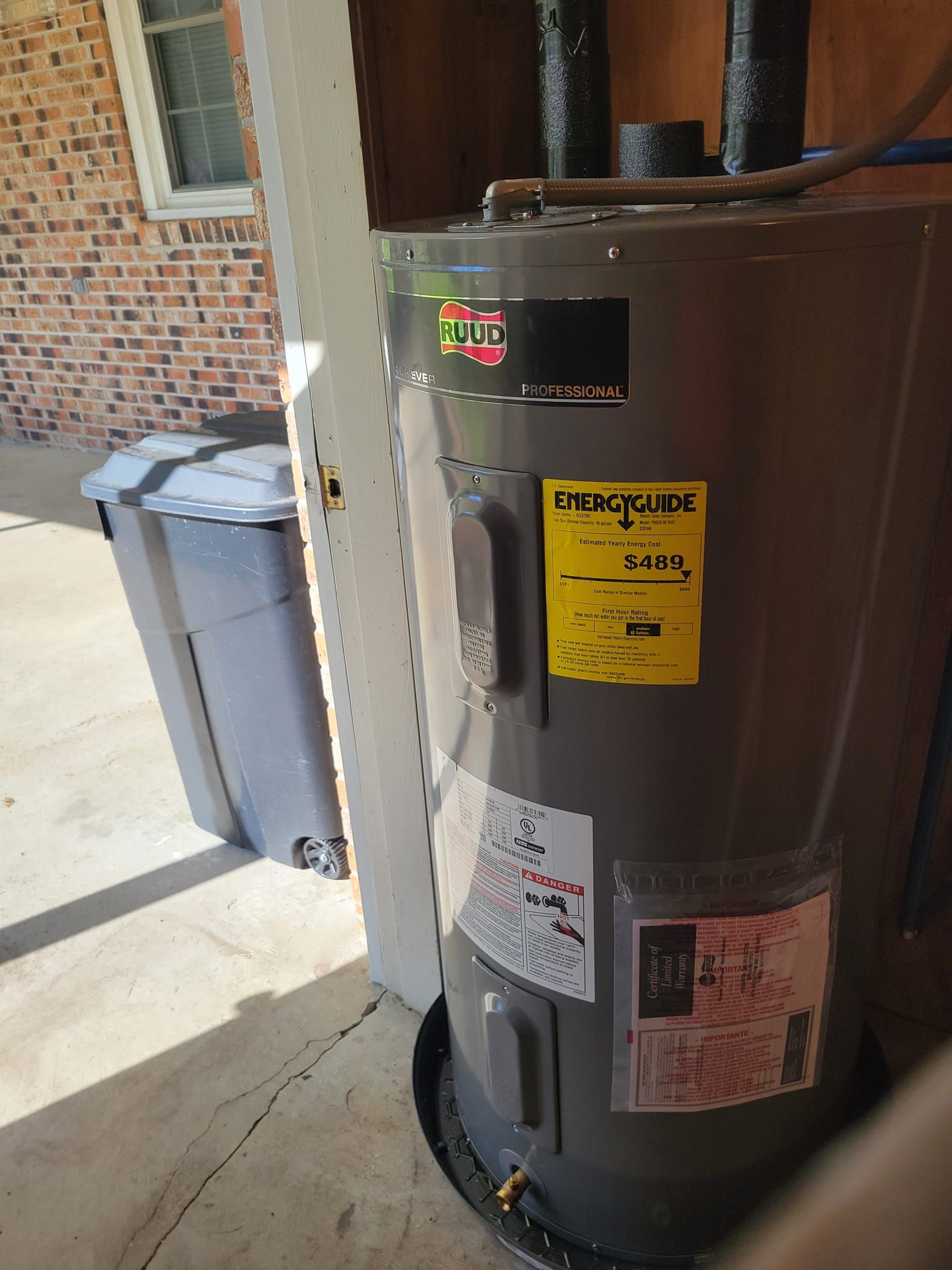 A water heater is sitting in a garage next to a brick wall