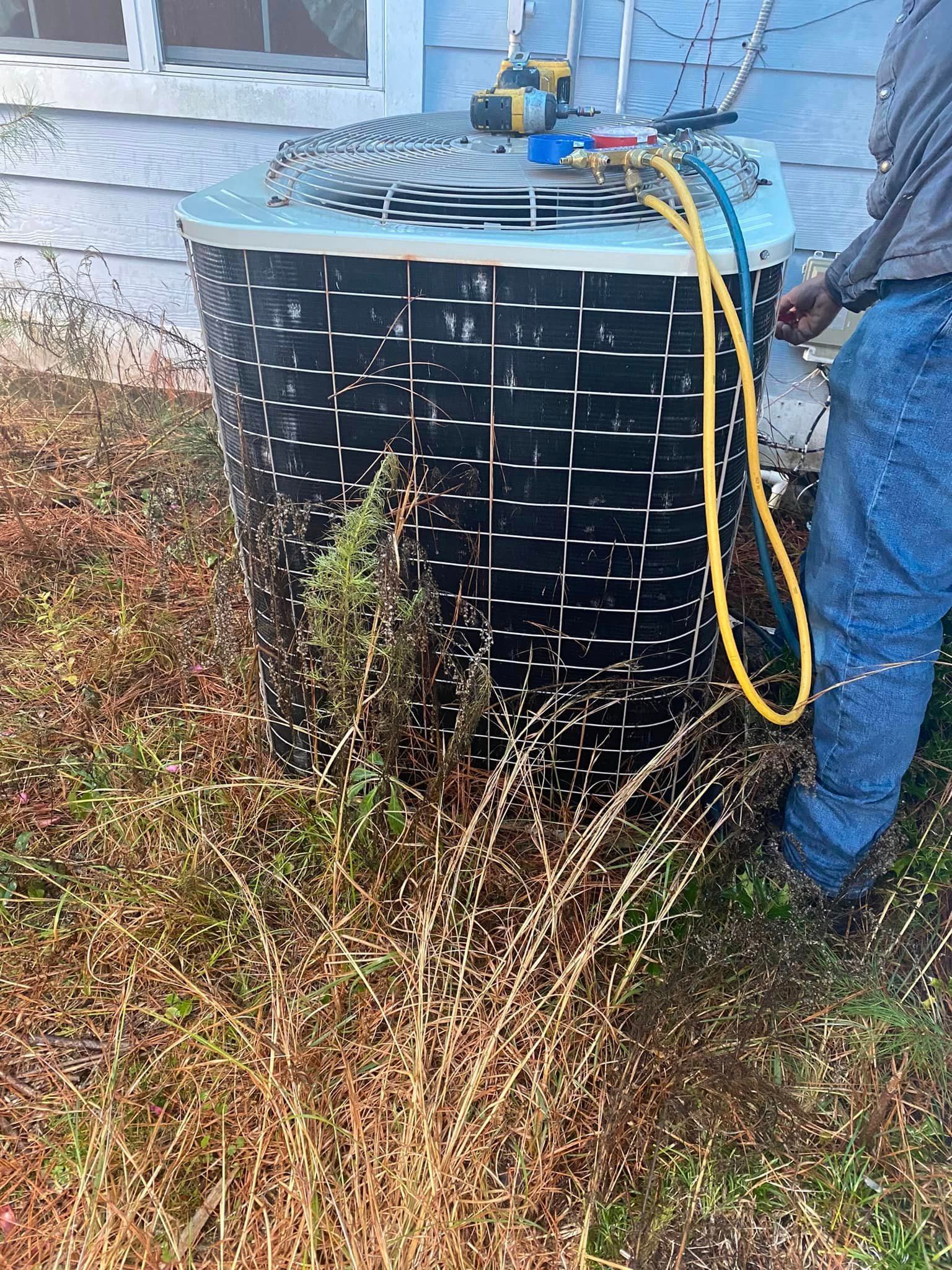 A man is working on an air conditioner outside of a house