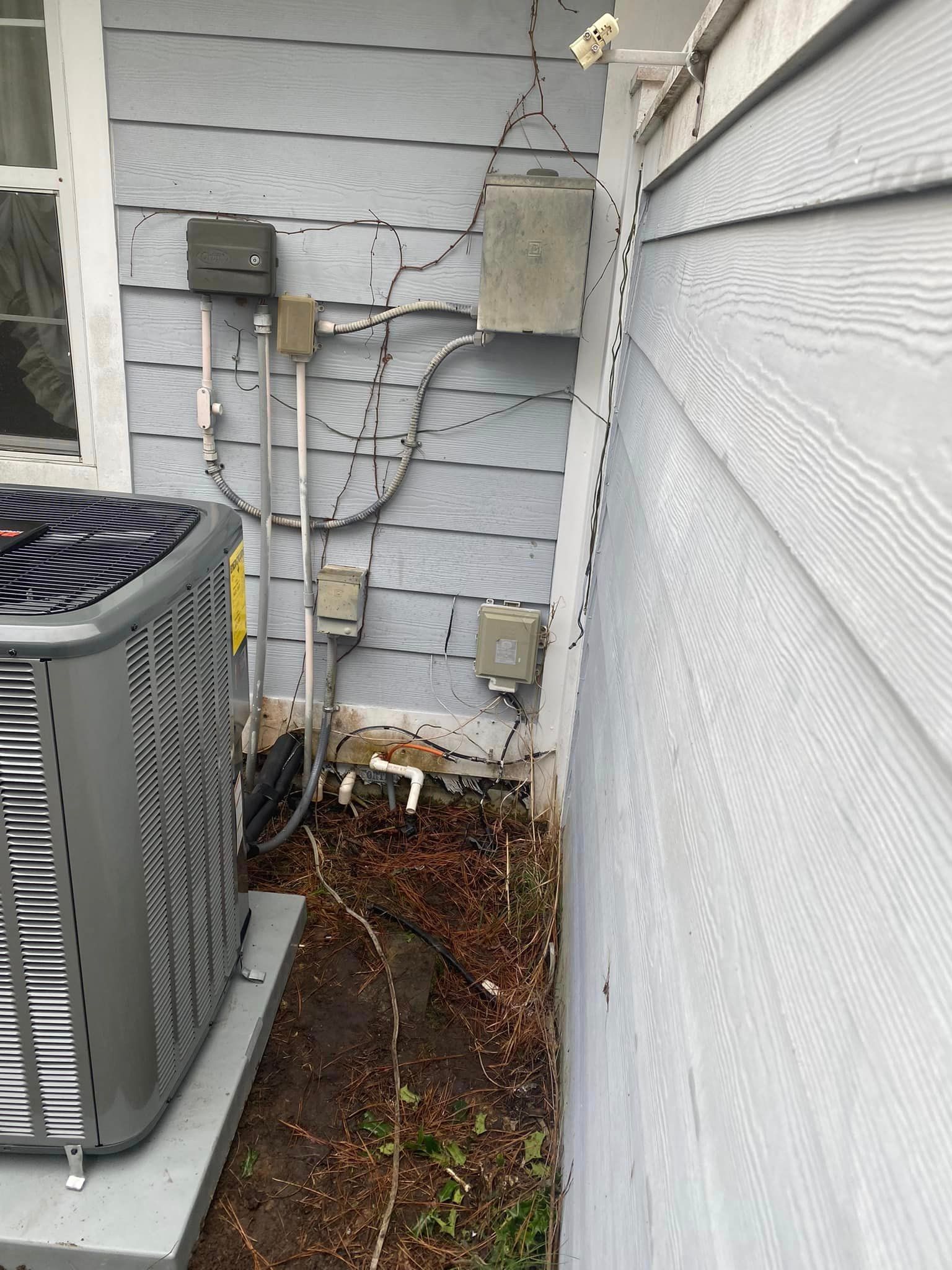 An air conditioner is sitting on the side of a house next to a window