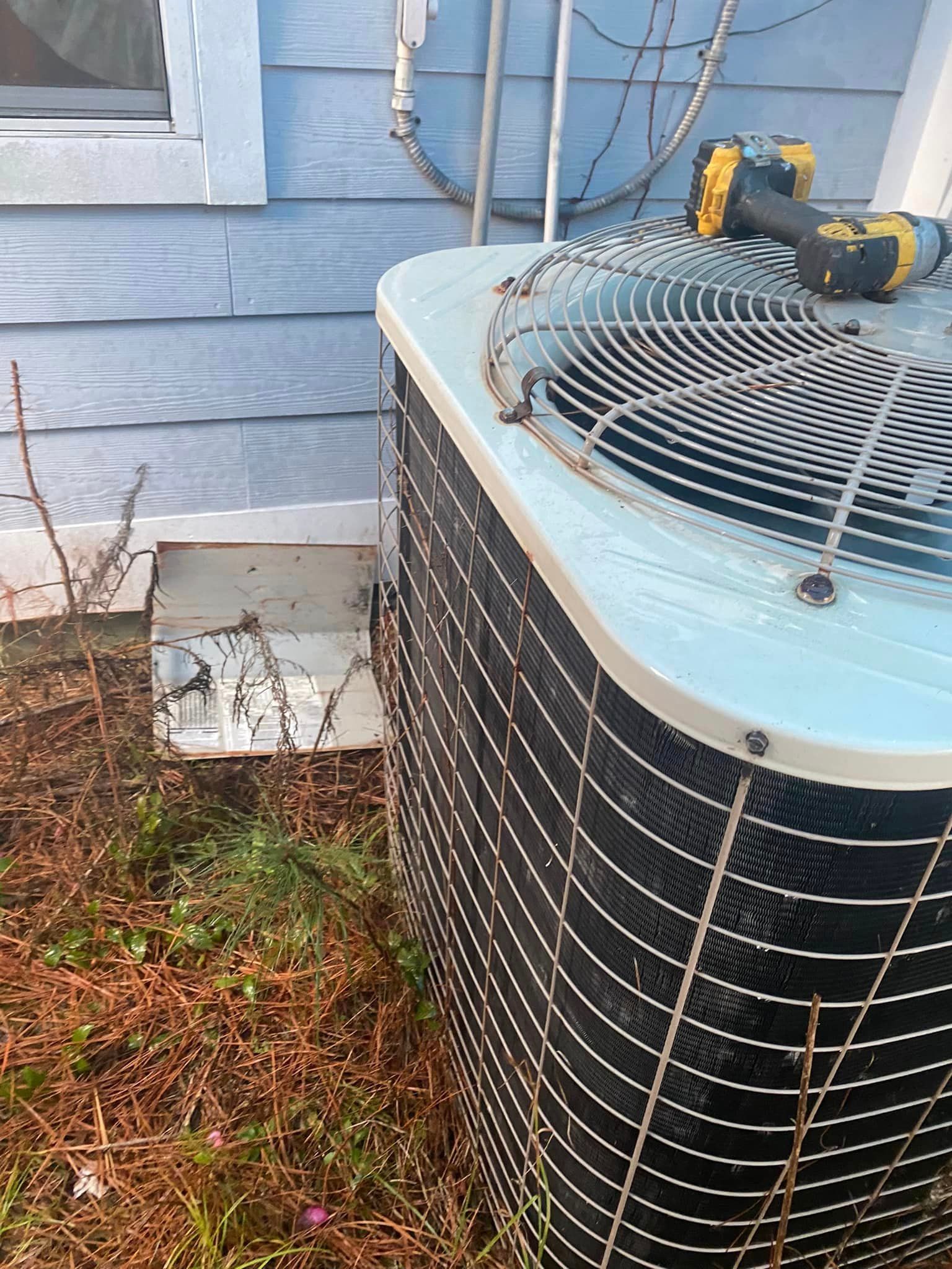 An air conditioner is sitting outside of a house next to a window