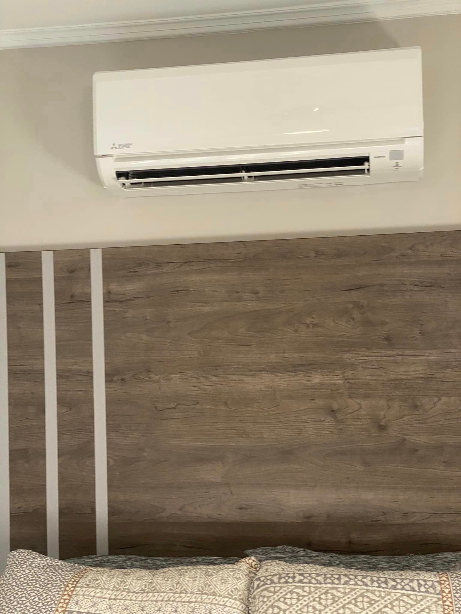A bedroom with a bed and a wall mounted air conditioner