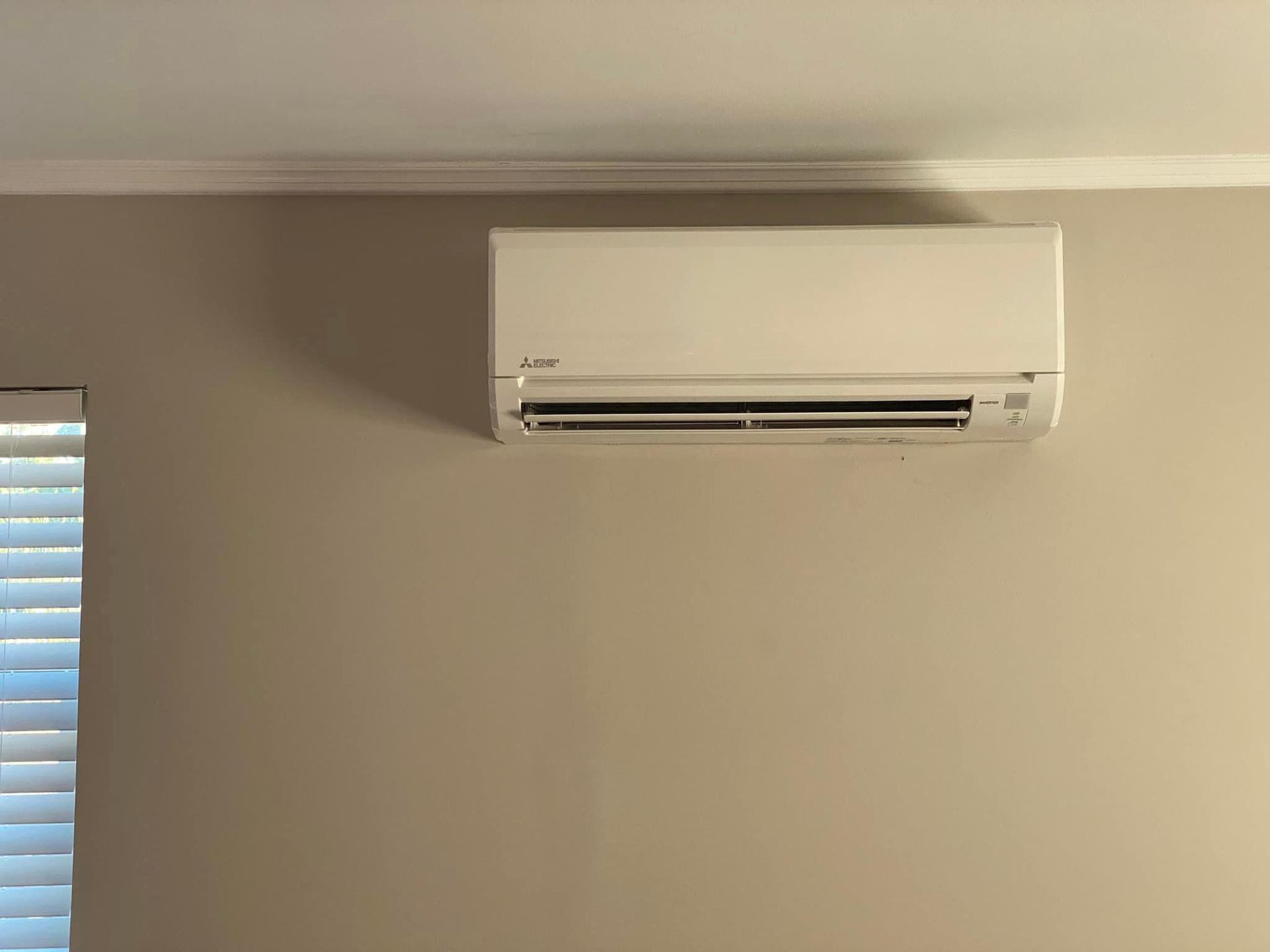 A white air conditioner is hanging on a wall next to a window