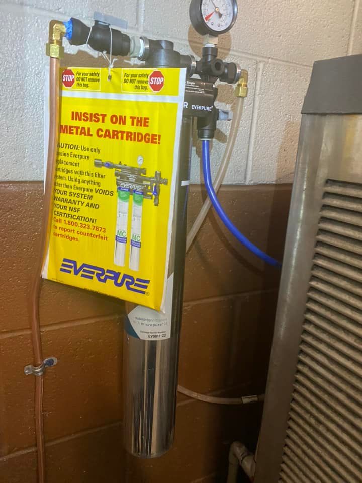 A stainless steel water filter is attached to a wall