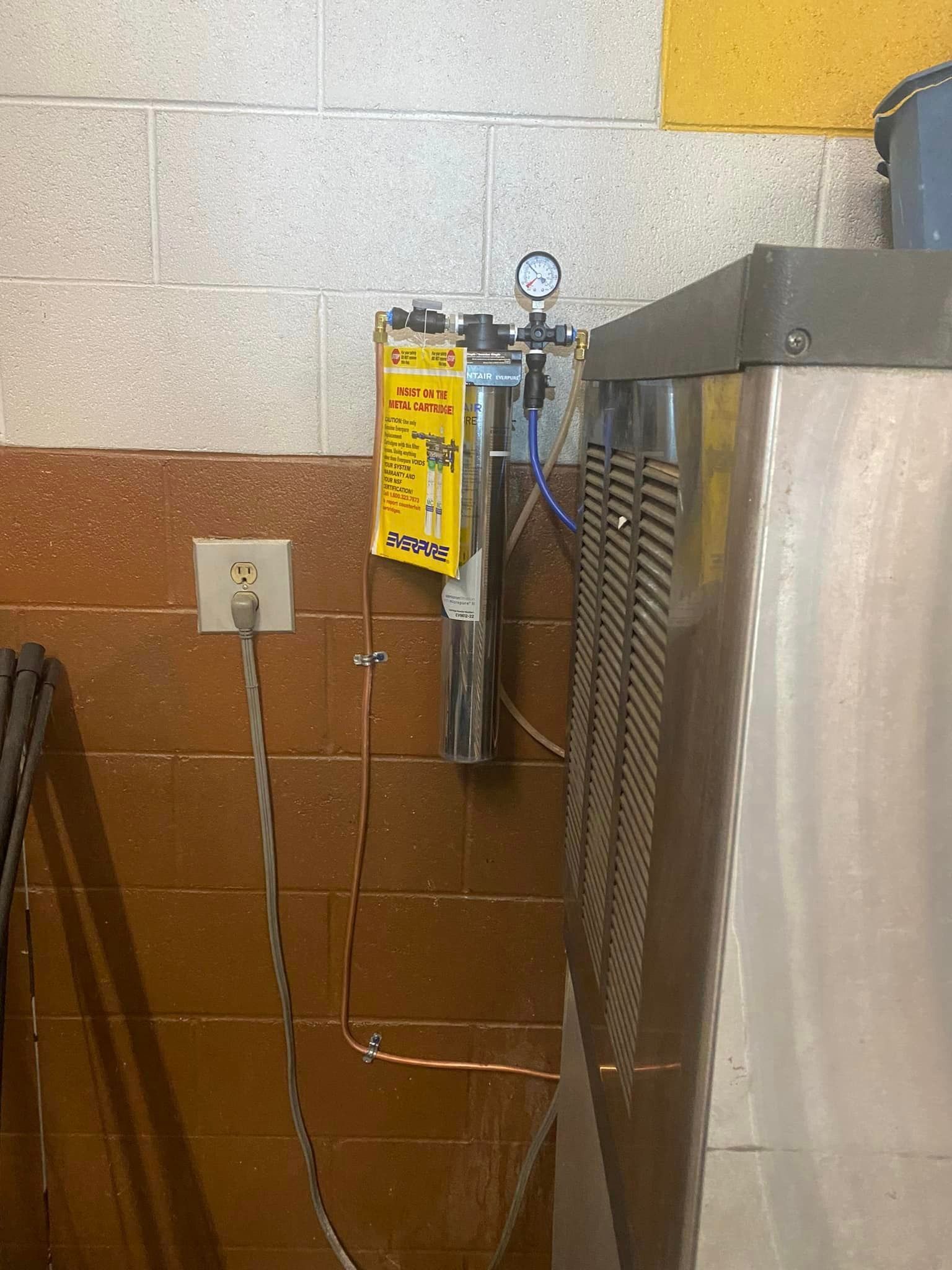 A stainless steel refrigerator is sitting in a room next to a brick wall