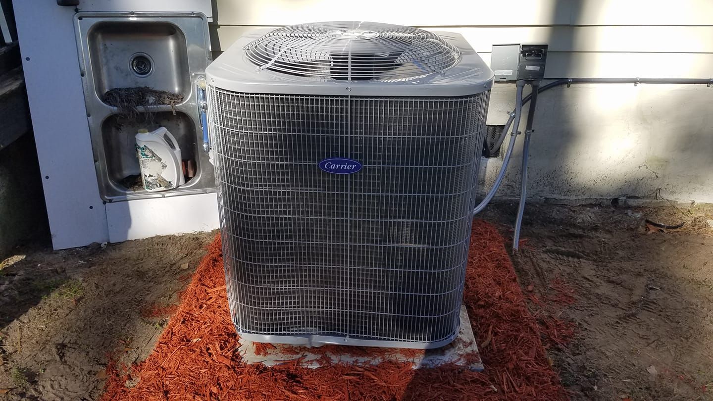 A carrier air conditioner is sitting on top of a pile of mulch