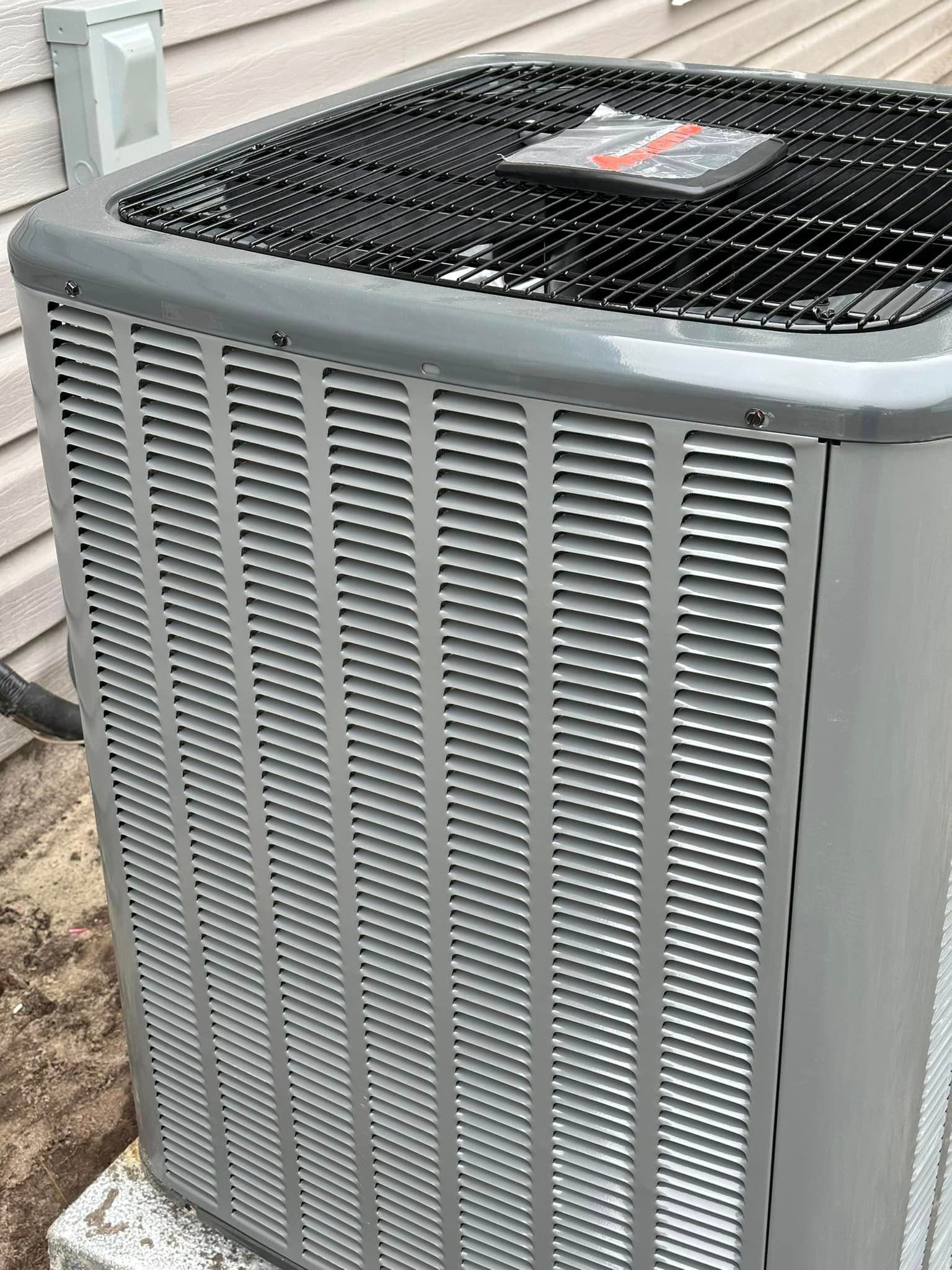 A large air conditioner is sitting outside of a house